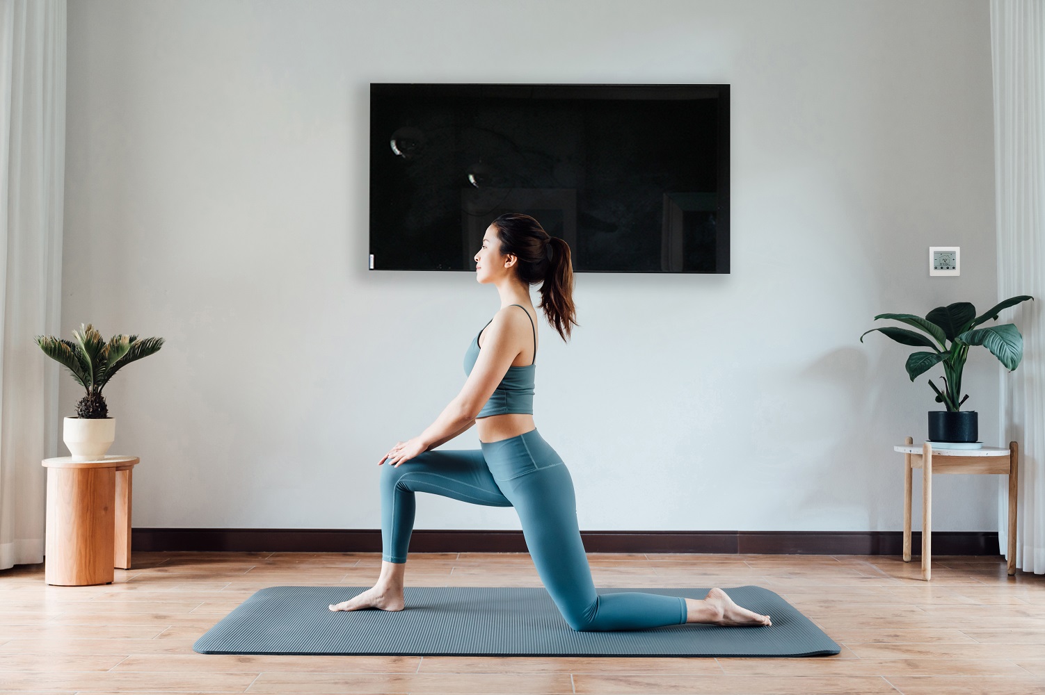 Un élégant panneau en verre noir réchauffe une femme faisant de l'exercice à la maison