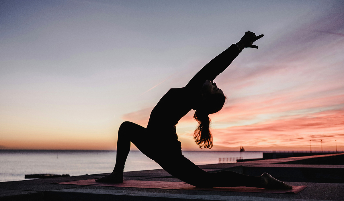 Personne faisant du yoga au coucher du soleil